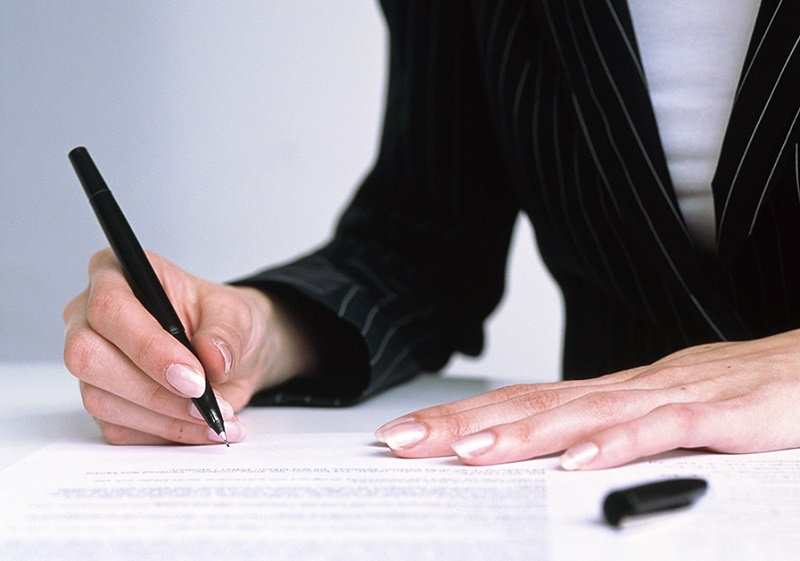 Kvinna skriver på avtal